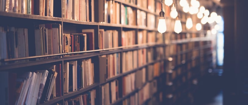 a long row of bookshelves with light bulbs and hanging lights