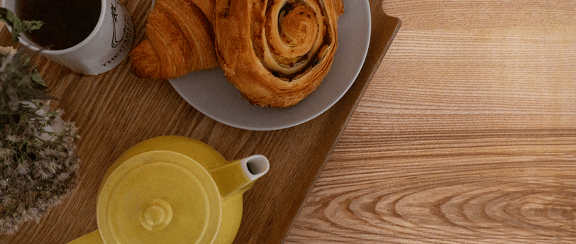Plateau de table en bois naturel avec bord live edge, vu de près. Seul un plateau de déjeuner est posé dessus, occupant presq