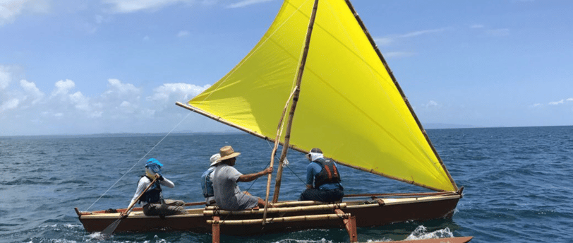 a group of people on a traditional style boat on the water in the Pacific