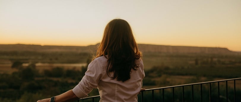 a woman standing on a balcony with a view of the sunset