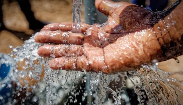 Hands catching flowing clean water from a faucet,