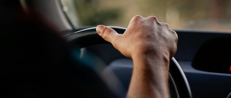 Person holding steering wheel