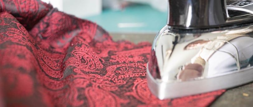 Fer à repasser sur un tissu brocard rouge et noir