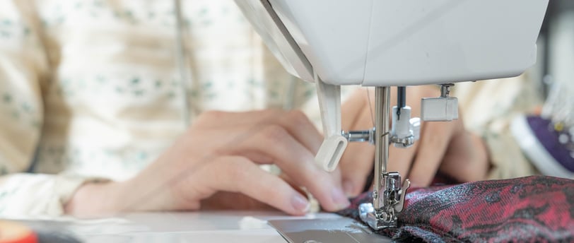 Mains guidant le tissu sur une machine à coudre