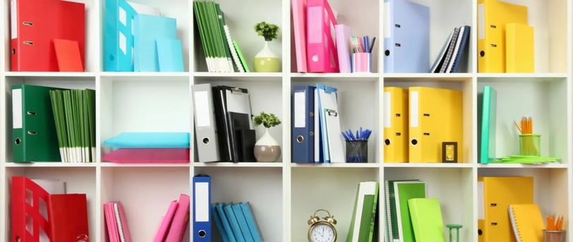 a bookcase with many different colored binders