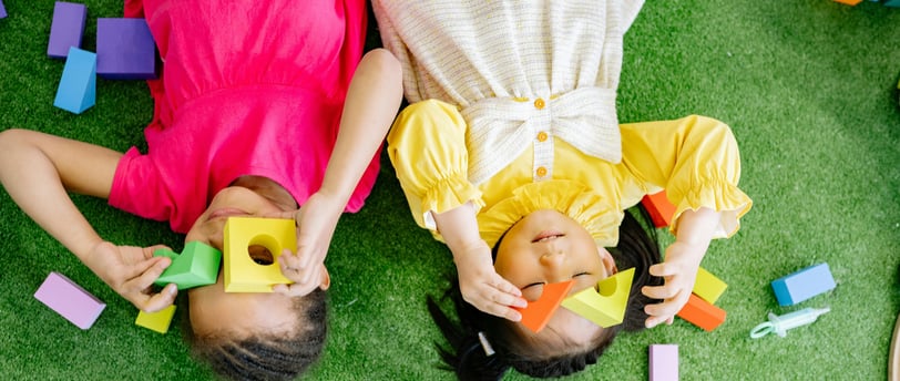 two children playing with blocks on a green carpet