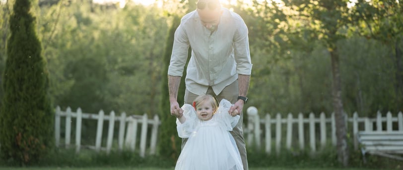a man and a baby girl walking in the grass