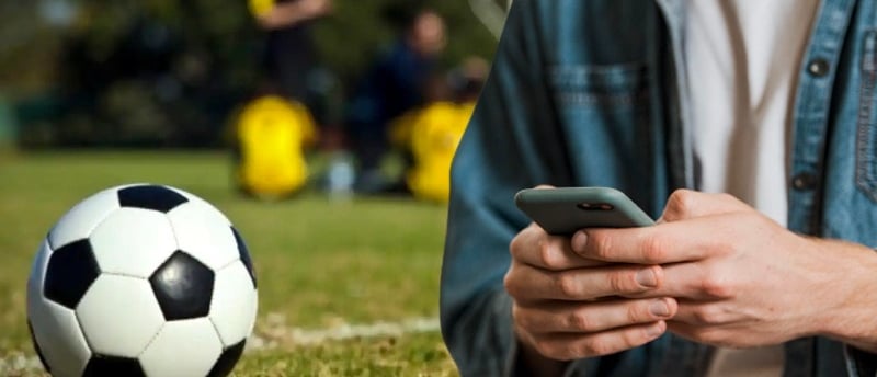 a man in a blue shirt is holding a cell phone