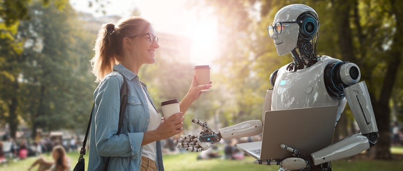 Moteris draugiškai bendrauja su robotu parke, siūlo jam kavos. Robos laiko kompiuterį rankose.