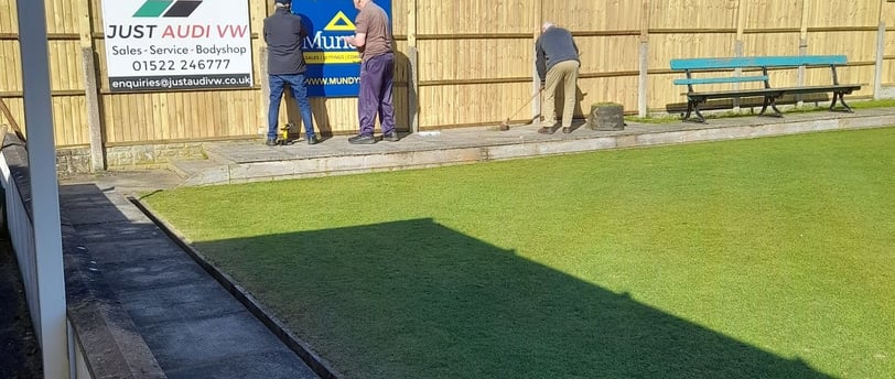 Members replace the sponsors signs on our new fence