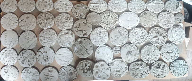 a bunch of clay tiles with different plants pressed in
