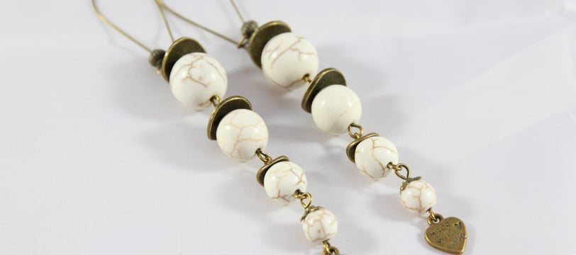 a pair of earrings with white marbled beads