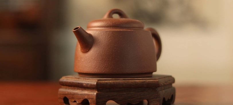 Brown teapot placed on a wooden stand