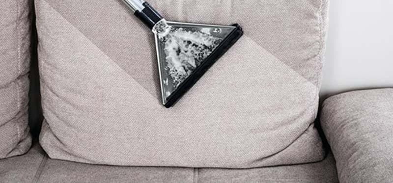 Um sofa sendo aspirado por uma maquina de limpeza de sofa