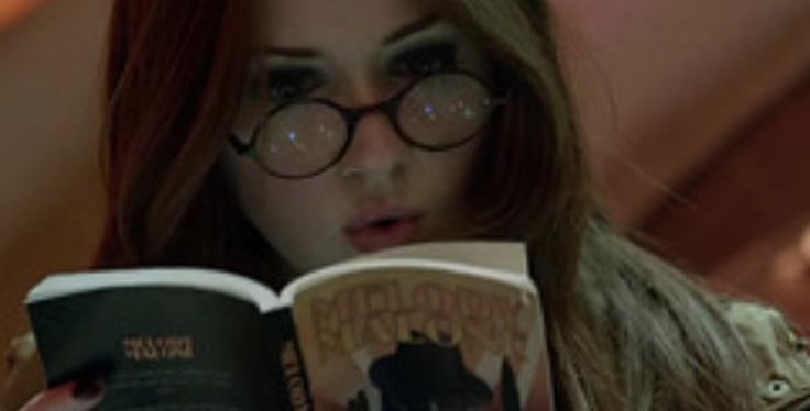 imagem da personagem amy pond da serie doctor who lendo um livro dentro da tardis.