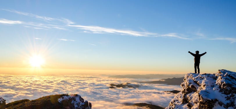 a person standing on a mountain top with arms spread wide