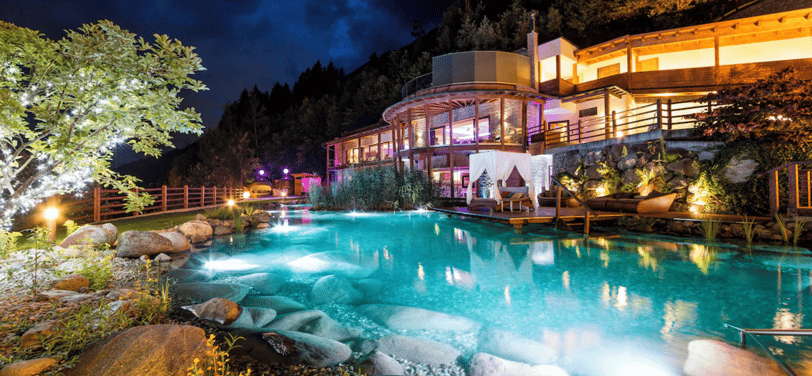 Großer Pool mit Blick auf ein Luxushotel bei Nacht