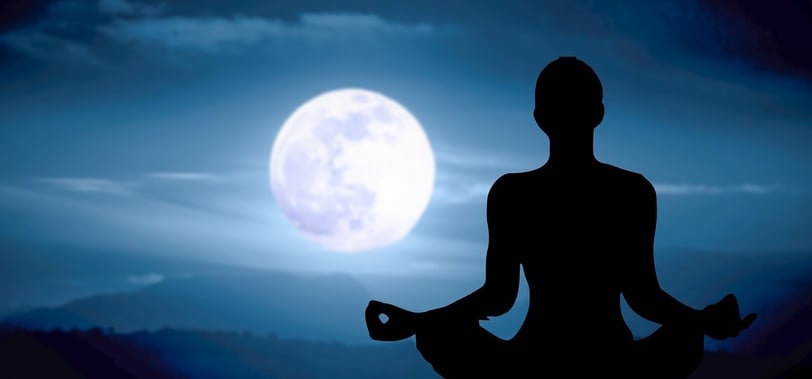 Silhouette of a person meditating under a full moon, representing mental clarity and mindfulness
