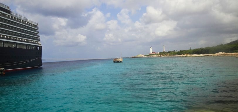 Vista do navio de cruzeiro ancorado na costa de Curaçao, com o mar azul e a cidade ao fundo.