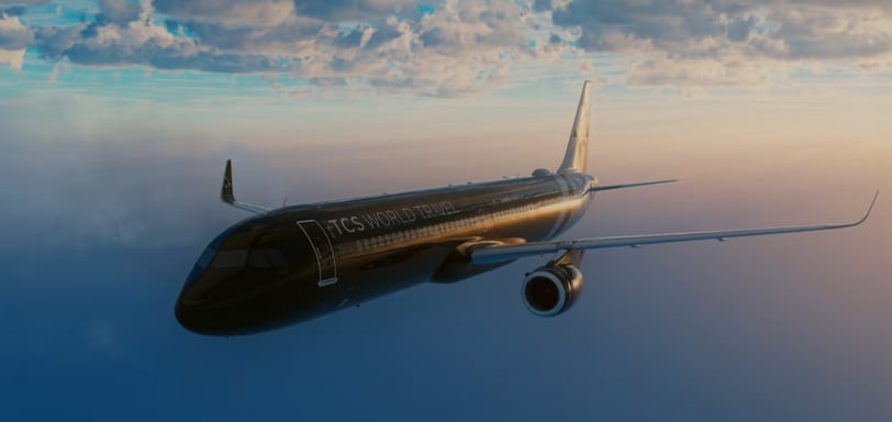 Luxury airplane in flight – Sleek black airplane labeled TCS World Travel flying at sunset.