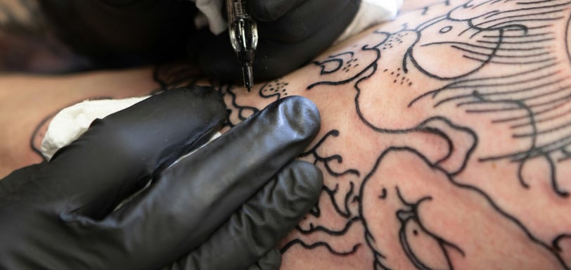Tatuador desenvolvendo sua arte no braço de um cliente