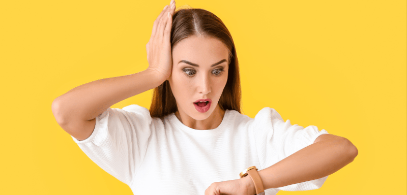 a woman looking a watch on her wrist with her hand on her head looking worried