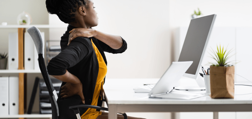 a woman sitting at a desk with a computer monitor and a monitor screen