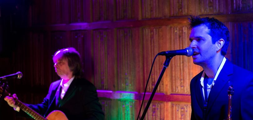 men in a suits playing guitar and saxophone