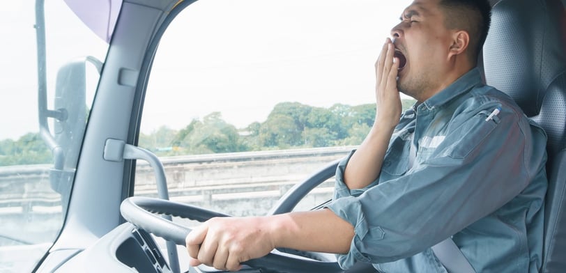 a man in a blue shirt is sitting in a truck yawning