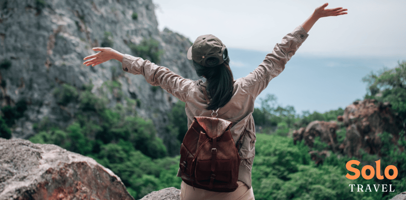 a woman with a backpack with her arms up and arms outstretched