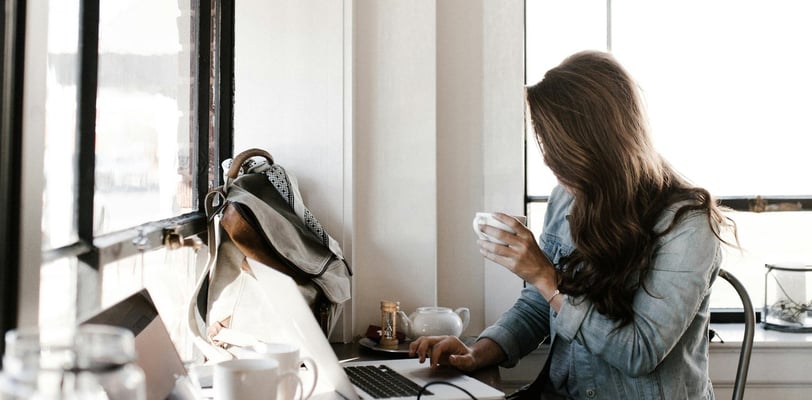 a woman sitting at a desk with a laptop and a cup of coffee