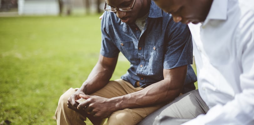 two men sitting on a bench in a park having a spiritual counseling meeting