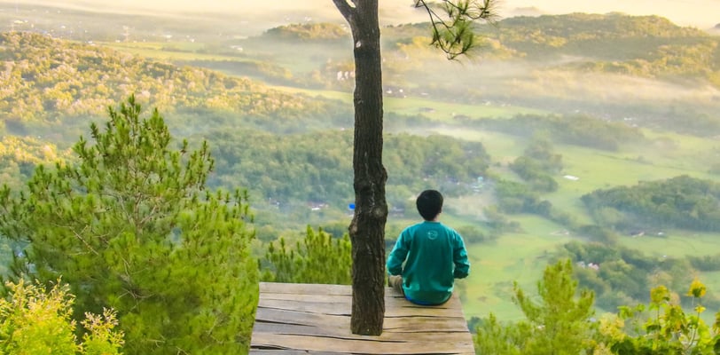 a man sitting on a tree house in the woods instantly boosting his mental health