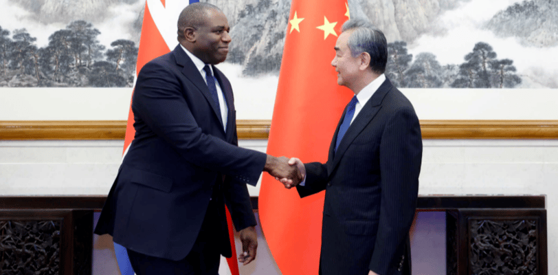 two men shaking hands in front of a chinese flag