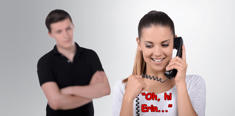 A man with a jealous look standing behind a woman talking on a phone