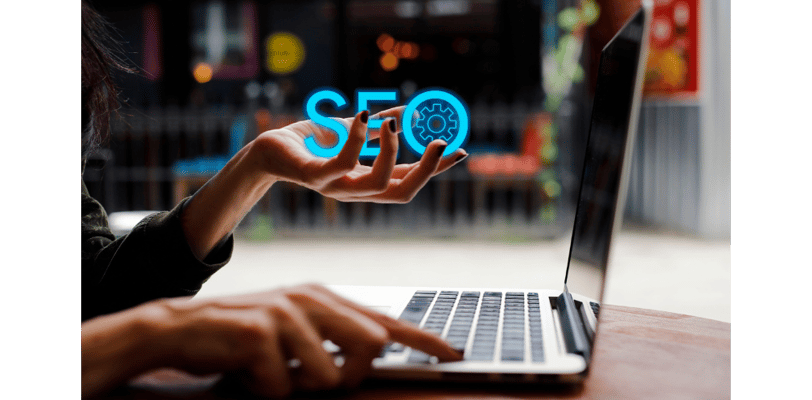 Digital marketing professional using laptop with a holographic SEO icon floating above hand