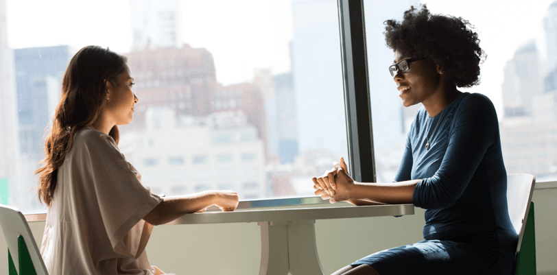 two women talking at a table supporting each other