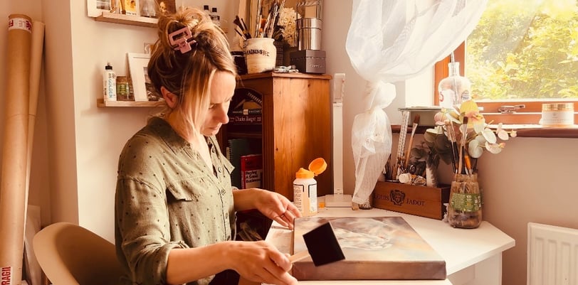 Applying the final layer of varnish to a painting