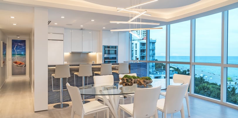 a modern dining room with a table and chairs with an ocean view