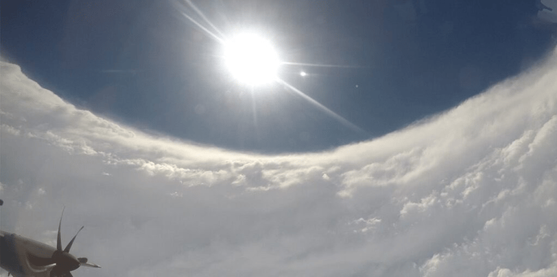 Hurricane Hunter flying in eye of hurricane looking out window, seeing plane engine and sun shinning about in clear eye.