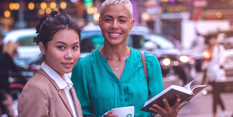 two women standing next to each other on a city street