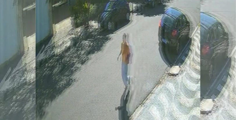 a woman walking down a street with a car parked in front of her