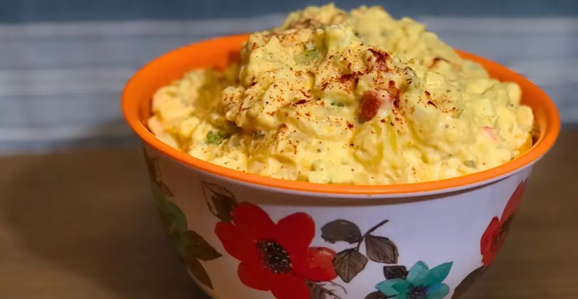 flowered bowl filled with southern potato salad on table.