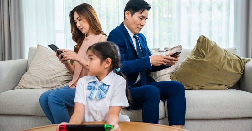 Mother, Father, and Child all looking at devices.