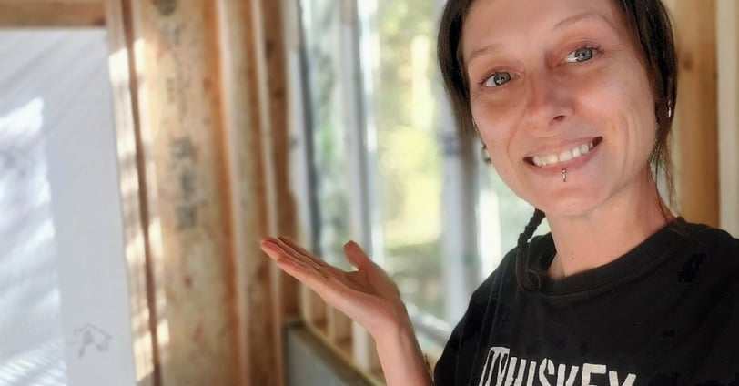 a woman smiling as she shows the construction progress of her dream studio space