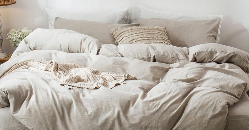 comfy bed with neutral tone bedding that looks lived in and a bit messy