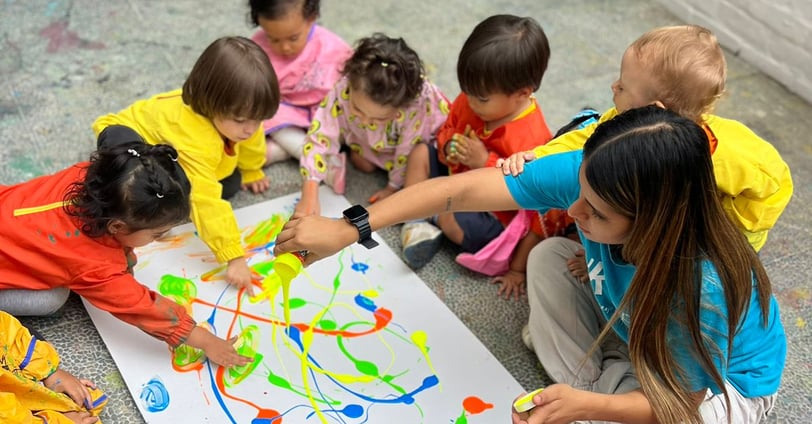 Niños con pinturas brillantes jugando sentados en el piso