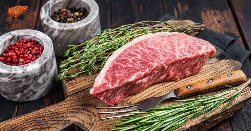 Wagyu Streak on a wooden board along with parsley and a fork, and black pepper