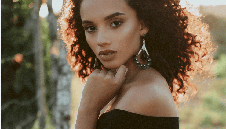 a woman with curly hair and earrings on her neck