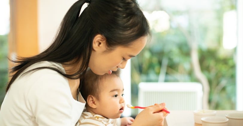 seorang ibu yang sedang menyuapi anaknya